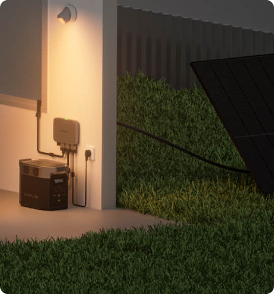 Home battery connected to an electrical outlet, with a portable solar panel in the grass next to the house.