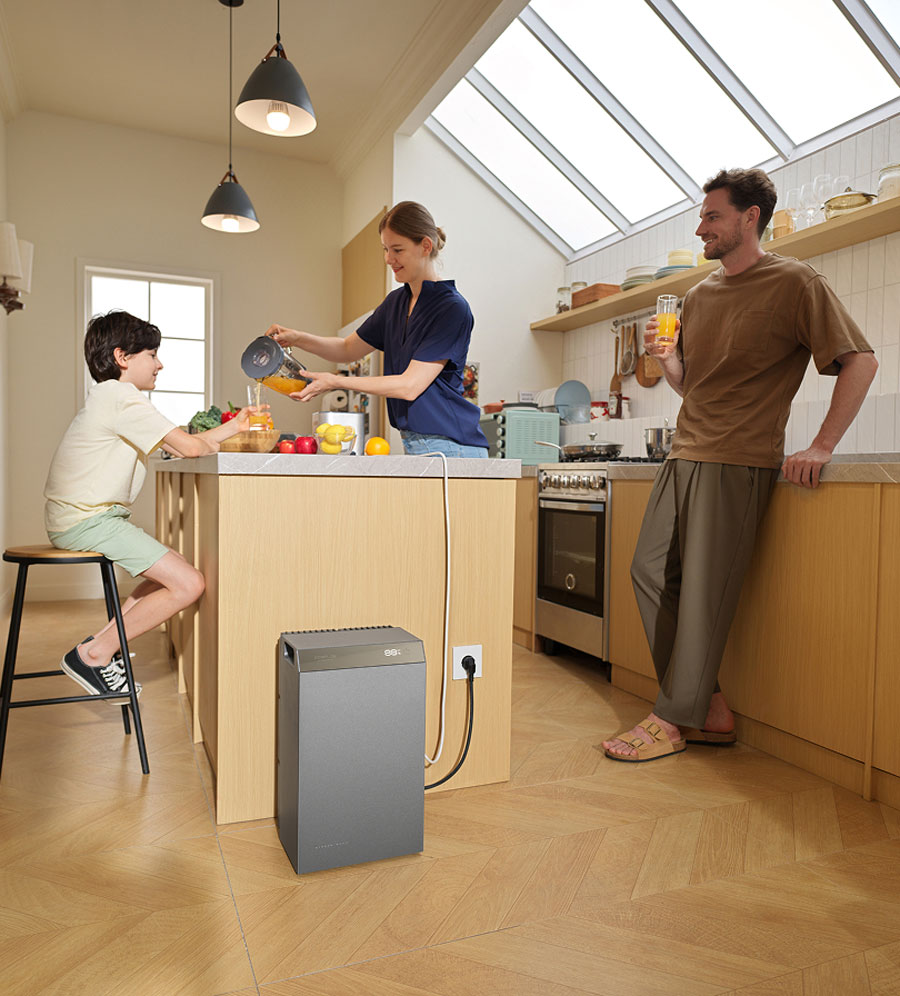portable powerstation grijs aangesloten in moderne keuken met gezin dat sinaasappelsap maakt en drinkt